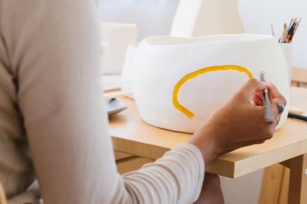 Focused African American ceramist painting pottery in workshop